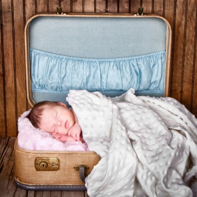 Une valise remplie de couvertures moelleuses et un nouveau né y dort paisiblement